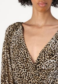 Abito con stampa leopardata caratterizzato da un profondo scollo a V, maniche fluttuanti e un tessuto testurizzato con accenti floreali bianchi.