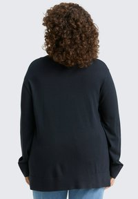 Zwarte gebreide trui met een relaxte fit, lange mouwen en een geribbelde zoom. Zachte textuur en een rechte rugdesign zonder versieringen.