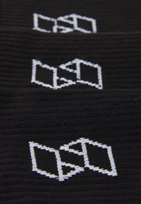Juodas tekstilės audinys, kuriame pavaizduota pakartotinė geometrinė logotipo dizaino struktūra balta spalva. Logotipas sudarytas iš tarpusavyje sujungtų formų, dekoruotų smulkia siuvinėjimo siūle.