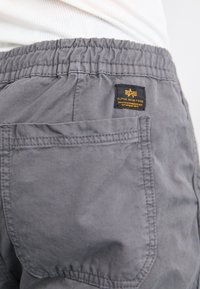 Shorts cargo en coton gris avec une taille élastique, dotés d'une poche plaquée et d'une étiquette noire avec du texte jaune. Fini en tissu durable.