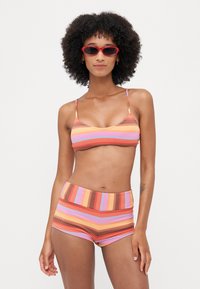 Csíkos bikini narancssárga, rózsaszín és barna árnyalatokban. Bralette fazonú felső vékony pántokkal, és magas derekú rövidnadrág, amely texturált anyagból készült.