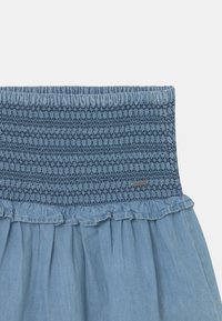 Blå denimkjol med en strukturerad smockad midjeband, volangkant och en mjuk finish. Har en liten märkesetikett på midjebandet.