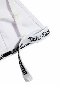 Balta bralete su reguliuojamomis petnešomis. Apatinėje dalyje yra juodas "Juicy Couture" logotipo juostos dekoras ir šiurkšti, švelni medžiaga.