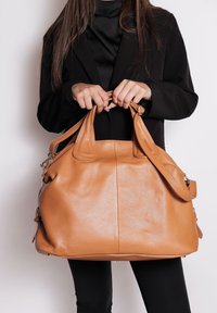 Borsa a mano in pelle tan con finitura testurizzata, doppi manici superiori e tracolla regolabile. Presenta un ampio interno e hardware in tonalità argento.