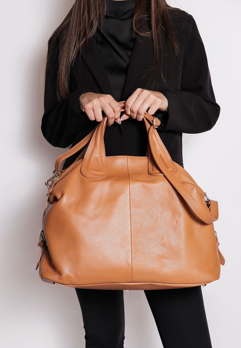 Borsa a mano in pelle tan con finitura testurizzata, doppi manici superiori e tracolla regolabile. Presenta un ampio interno e hardware in tonalità argento.