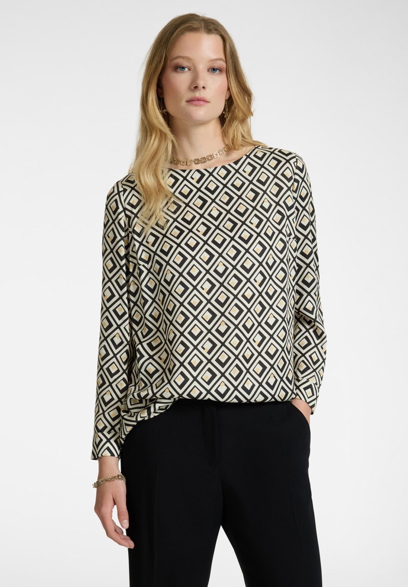 Långärmad topp med ett svart och vitt diamantmönster med gula accenter. Mjuk tyg och avslappnad passform; rund halsringning. Matchas med svarta byxor.