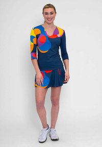 Conjunto deportivo de color marino que incluye una blusa ajustada con círculos de colores, mangas de tres cuartos y una falda acampanada con acentos en rojo y azul.