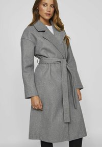 Cappotto grigio in lana con cintura, ampi rever e maniche lunghe. Presenta un design di lunghezza media e una finitura testurizzata e morbida.