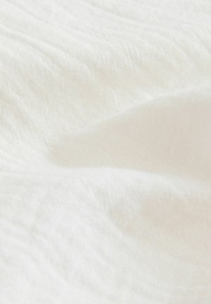 Witte stof met een gestructureerd oppervlak, gekenmerkt door zachte, vloeiende plooien en lichte onregelmatigheden. Het materiaal lijkt licht en luchtig.
