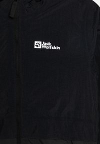 Zwarte lichtgewicht jack met een ritssluiting, textuurstof en een wit logo van "Jack Wolfskin" met een pootafdruk.