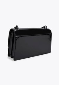 Borsa a mano rettangolare nera lucida con tracolla a catena, caratterizzata da un design elegante e strutturato su uno sfondo bianco.