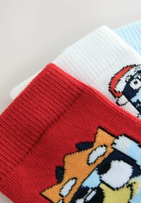Colorful socks featuring a red cuff with a cartoon character, a white and a light blue sock with distinct patterns and textures.