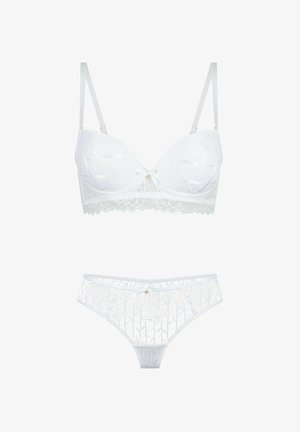 Witte kanten bh en bijpassend slipje met bloemmotieven en kleine decoratieve strikjes aan de voorkant in het midden.
