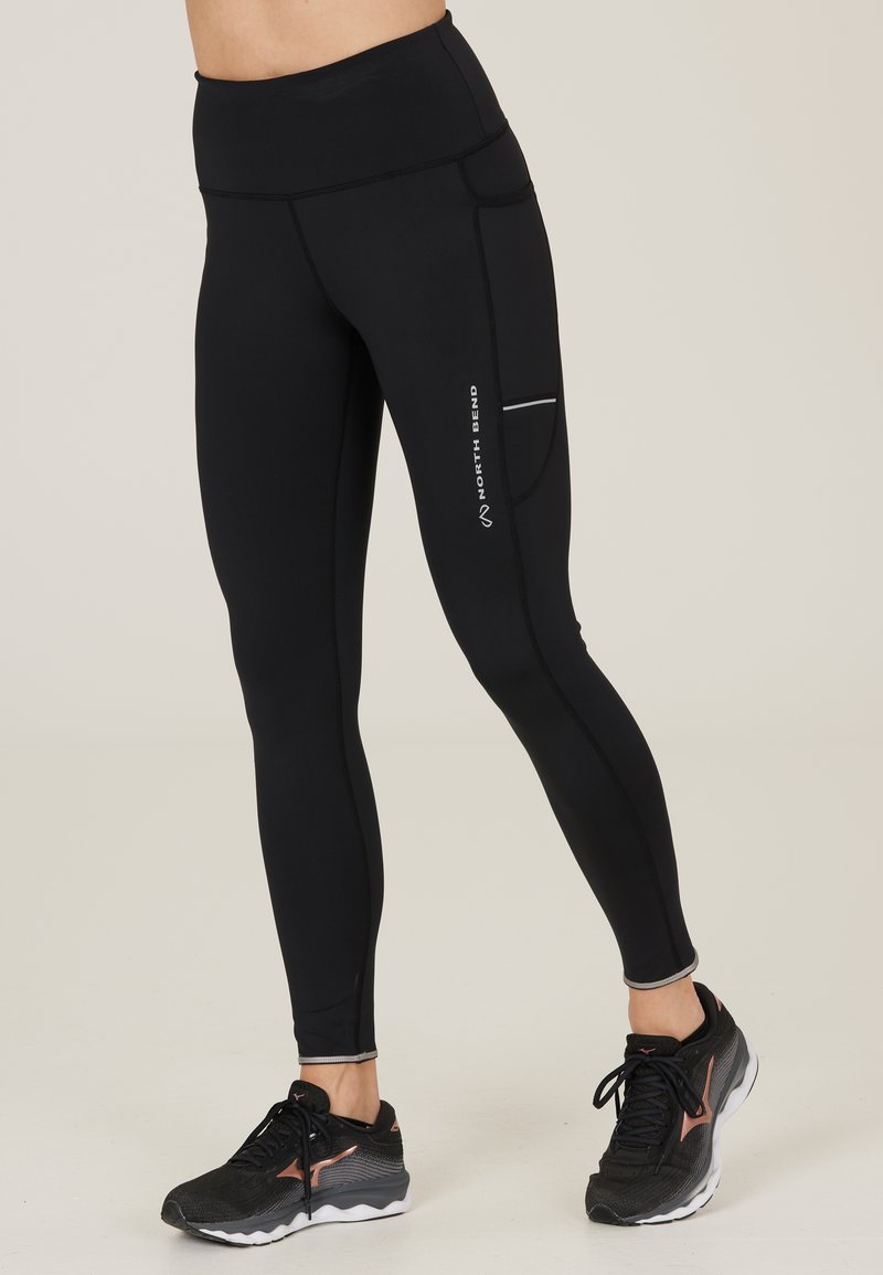 Mustat urheiluhousut korkean vyötärönauhan kanssa, jossa on sivutasku ja heijastavat yksityiskohdat sauman varrella. Silkkinen, joustava kangas.