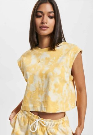 Geel tie-dye crop top met opgerolde mouwen, voorzien van een klein gouden Nike-logo op de borst. Gemaakt van zachte katoen met een relaxed fit.