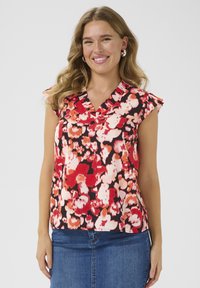 Haut sans manches à motif floral avec un décolleté en V, présentant un mélange de fleurs rouges, roses et blanches sur un fond noir. Tissu doux avec des accents de volants.