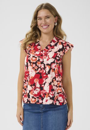 Mouwloze top met bloemenpatroon en een v-hals, met een mix van rode, roze en witte bloemen op een zwarte achtergrond. Zachte stof met ruches.