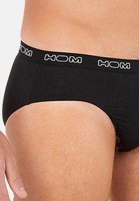 Zwarte katoenen boxershorts met een strakke pasvorm, voorzien van een wit "HOM" logo op de elastische tailleband. Gladde textuur, eenvoudig ontwerp zonder extra patronen.