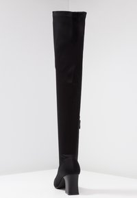 Botte noire au-dessus du genou en tissu lisse ; comprend un talon bloc et un design ajusté, avec des détails de couture à l'arrière et sur le côté.