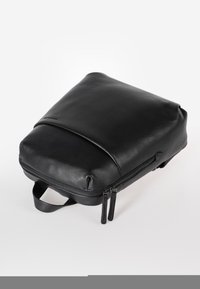 Zaino in pelle nera con superficie texture, dotato di un pannello inferiore liscio, chiusura con doppia cerniera e manico superiore per il trasporto.