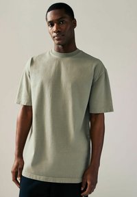Överdimensionerad t-shirt med korta ärmar i dämpad olivgrön, tillverkad av mjuk bomull, med rundad halsringning och avslappnad passform.