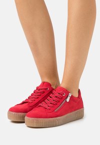 Baskets en daim rouge avec un design lacé texturé, une fermeture éclair latérale et une semelle en caoutchouc. Caractérisées par des coutures en relief et des accents perforés.