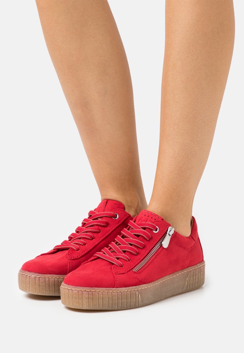 Baskets en daim rouge avec un design lacé texturé, une fermeture éclair latérale et une semelle en caoutchouc. Caractérisées par des coutures en relief et des accents perforés.