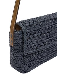 Woven navy bag with a textured finish, featuring a brown leather strap and a flap closure. Square shape with structured sides.