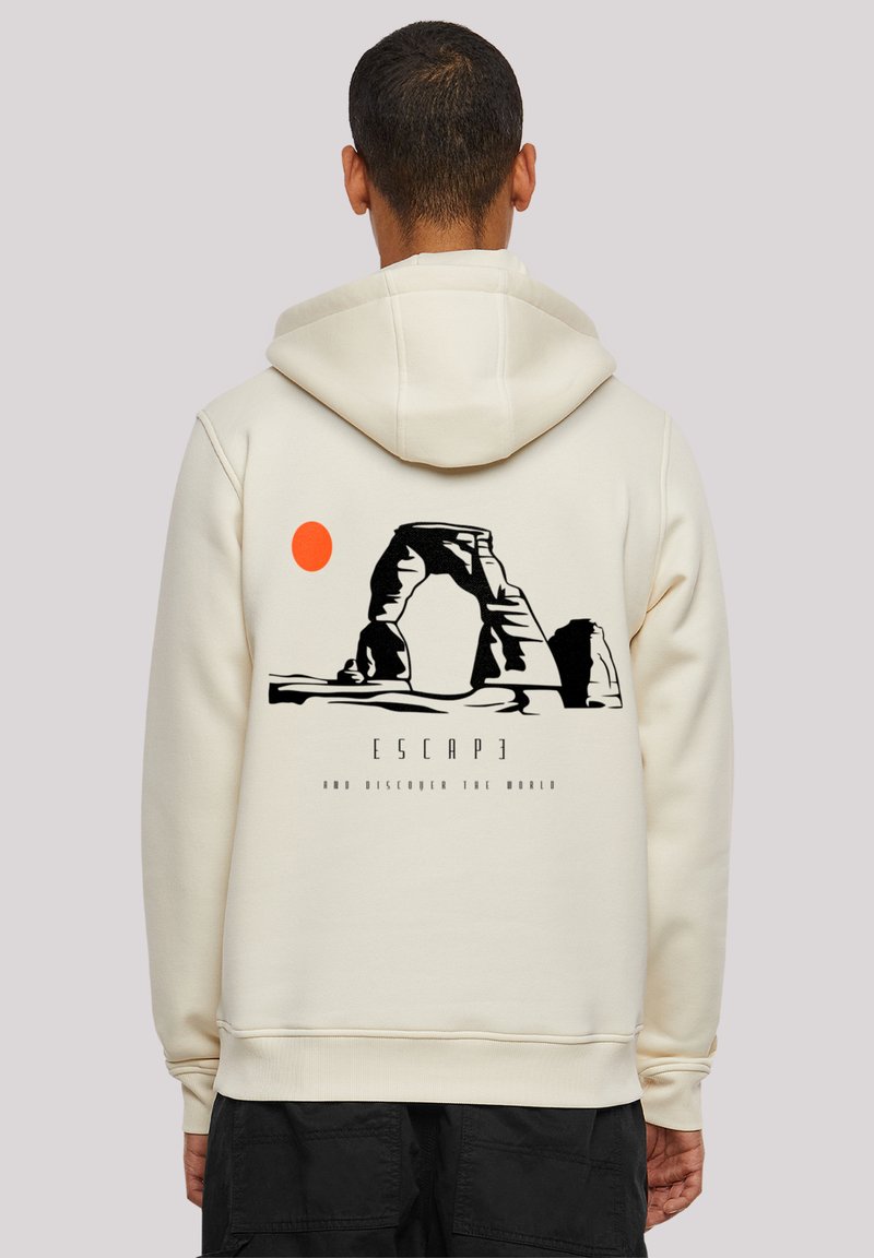 Beige hoodie with a graphic design featuring an arch, orange sun, and text "ESCAP3 AND DISCOVER THE WORLD" in black below the arch.