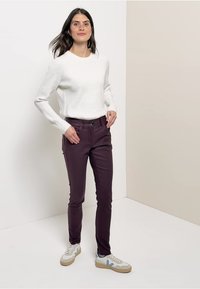 Pull en tricot blanc, pantalon slim burgundy et baskets blanches avec des accents bleus. Design simple et épuré avec une coupe décontractée.