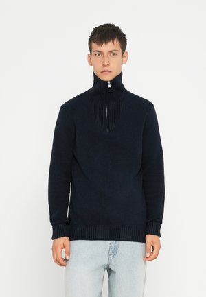 Pull en maille marine avec col haut et fermeture éclair demi-zip. Présente un col en V texturé et des poignets et un ourlet côtelés.