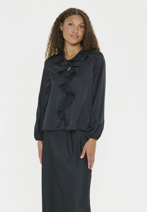 Black blouse with long sleeves, ruffled front detail, collar, and relaxed fit. Smooth fabric with slight sheen, paired with a matching skirt.