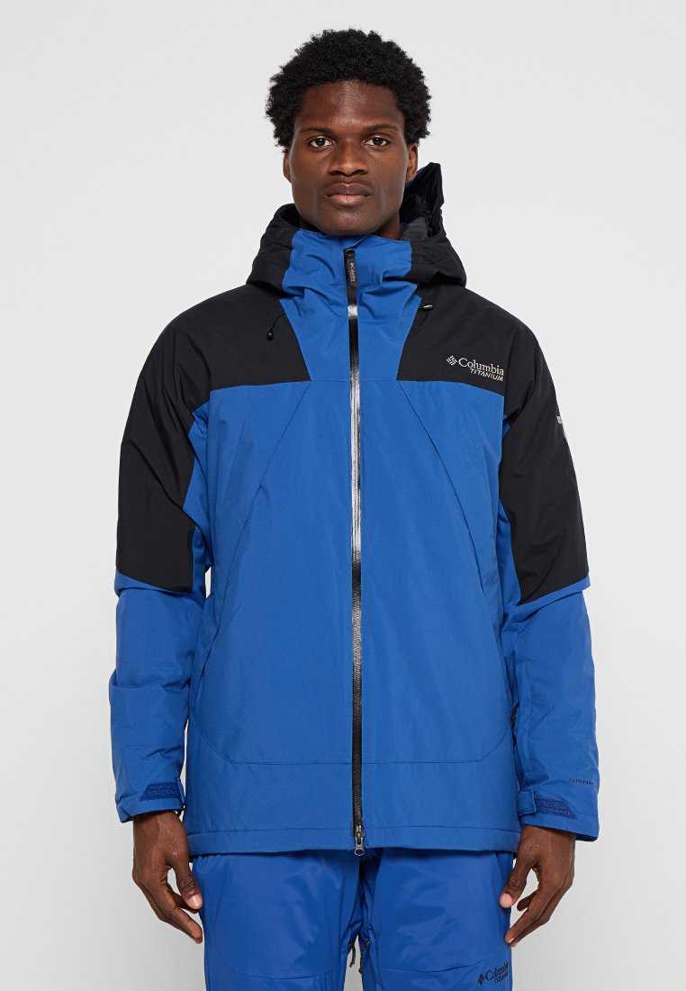 Blaue und schwarze isolierte Jacke mit Reißverschluss auf der Vorderseite, verstellbarem Kapuzenbereich und Seitentaschen. Mit einem Logo auf der Brust und unterschiedlich strukturierten Panels.