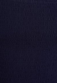 Tessuto textured blu navy con un motivo stropicciato, realizzato in materiale morbido e elasticizzato, ideale per abbigliamento aderente. Nessun ulteriore dettaglio visibile.