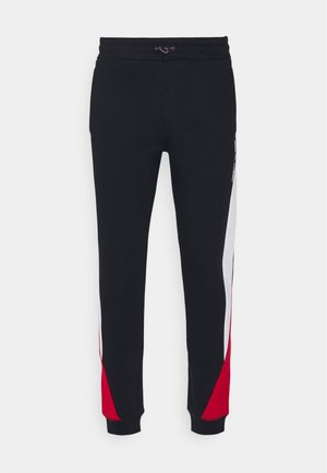 Zwarte sweatpants met elastische tailleband, voorzien van rode en witte zijpanelen. Gemaakt van zacht materiaal met ribbelmanchetten.