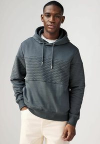 Hoodie in donkergrijs, met een textuur van honingraatpatroon over de borst. Zachte stof met geribde manchetten en zoom.