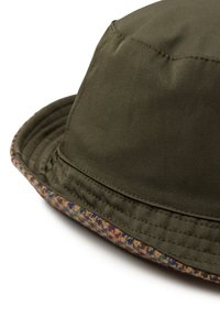 Gorro de cubo verde oliva con un ala texturizada y de patrón marrón. Presenta costuras cosidas y una composición de tela suave.