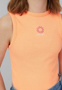 Oranje geribde mouwloze top met een roze zonafbeelding en de tekst "CHILL OUT." Het materiaal is zacht en aansluitend.