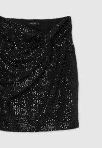Mini gonna nera in paillettes con design drappeggiato. Presenta una texture liscia e una superficie brillante, creando un effetto scintillante. Etichetta visibile.