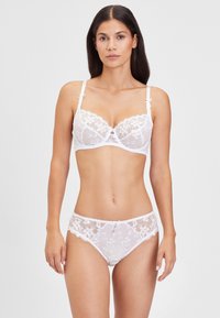 Weißes Spitzenunterwäsche-Set, bestehend aus einem transparenten BH mit floraler Stickerei und einem passenden Slip, beide mit zarten Verzierungen und Akzentdetails.