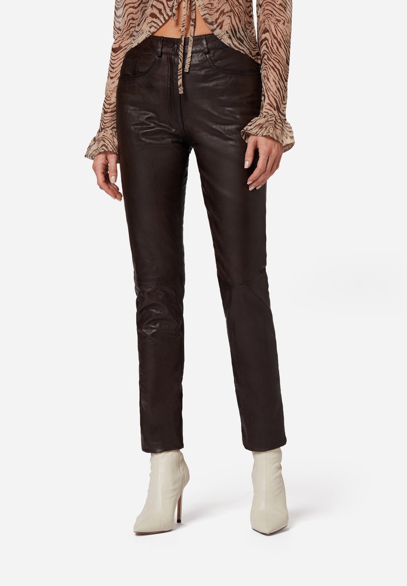 Zwarte leren broek met een slim fit, met een gladde textuur en minimale stikdetails. Gecombineerd met witte hakken.