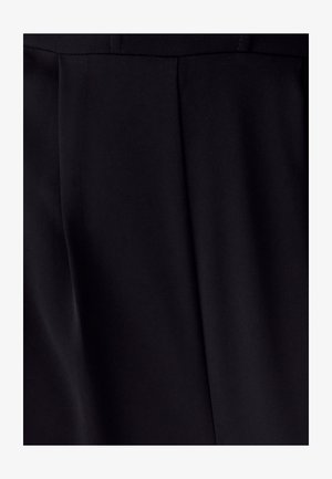 Close-up van zwarte stof met verticale plooien en subtiele diagonale textuur in zachte verlichting.