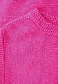 Pull tricoté rose vif mettant en avant le col côtelé et les détails texturés du tissu.