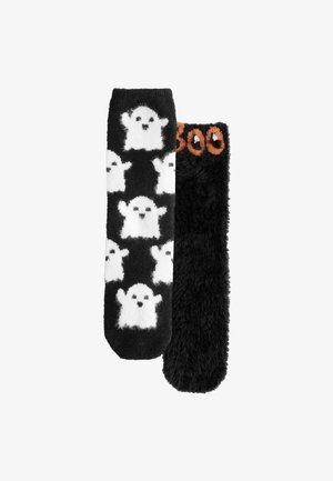 Une paire de chaussettes noires en peluche ; l'une des chaussettes arbore des motifs de fantômes blancs, tandis que l'autre a "Boo" écrit en orange près du haut.
