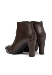 Brown leather ankle boots with a smooth texture, a rounded toe, and a 3-inch heel. Features minimal stitching and a zip closure at the back.
