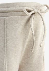 Beige Sweatpants mit einem Kordelzugbund, weichem Material und seitlichen Taschen mit sauberen Nahtdetails. Flexibles und lässiges Design.
