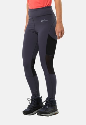 Purple high-waisted leggings with black mesh panel accents; stretchy fabric. Paired with black hiking boots featuring a textured sole.