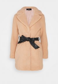 Faux fur frakke i blød fersken med spidskrave, lange ærmer og en sort bundet bælteaccent. Har tekstureret overflade og skræddersyet form.