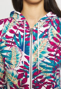 Hooded zip-up sweatshirt featuring a vibrant floral pattern in pink, teal, and beige, with a textured fabric and drawstring accents.