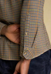 Karierter Hemd mit einer Mischung aus Blau, Braun und Grün, mit einem geknöpften Manschette und strukturiertem Stoff.